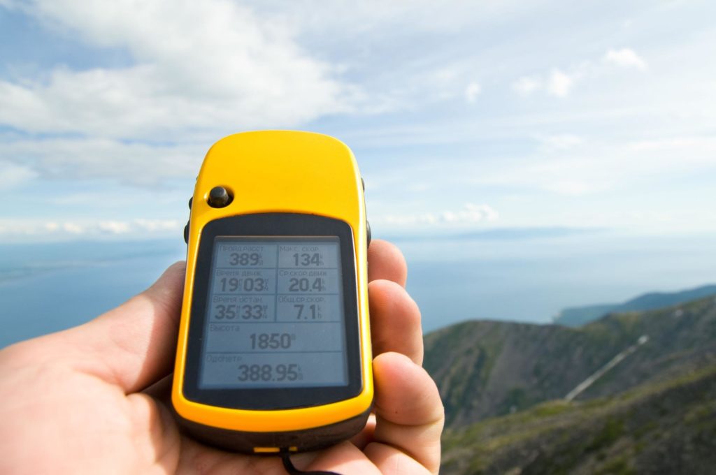 GPS-Gerät in der Hand beim Camping, Teil der technischen Ausrüstung zur Navigation in der Natur.