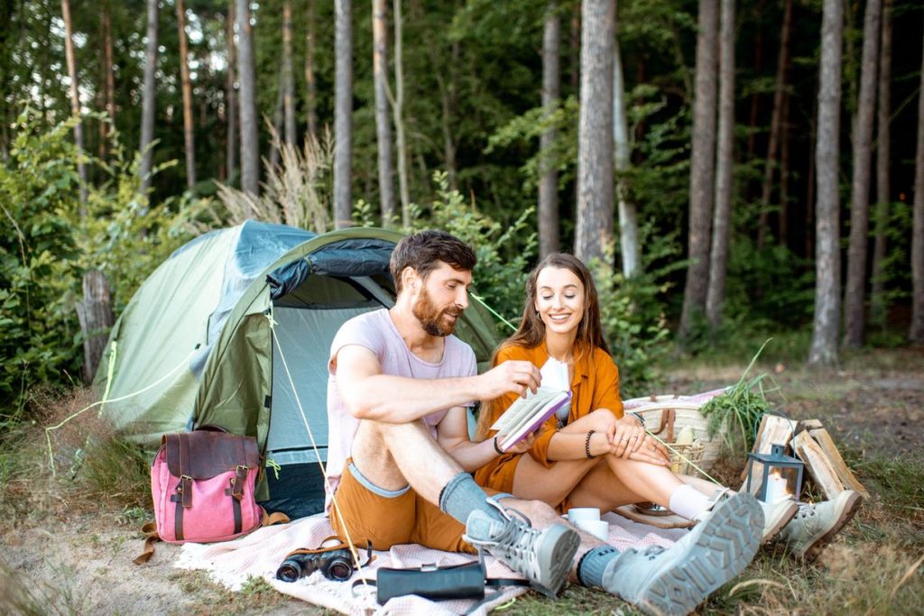 Paar beim Campen, entspannt vor ihrem Zelt in der Natur.