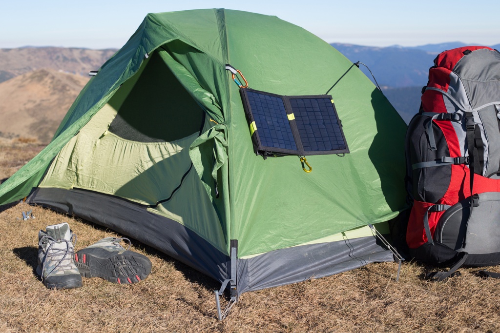 Grünes Campingzelt mit Solarpanel an der Seite, umweltfreundliche Energieversorgung in der Natur.