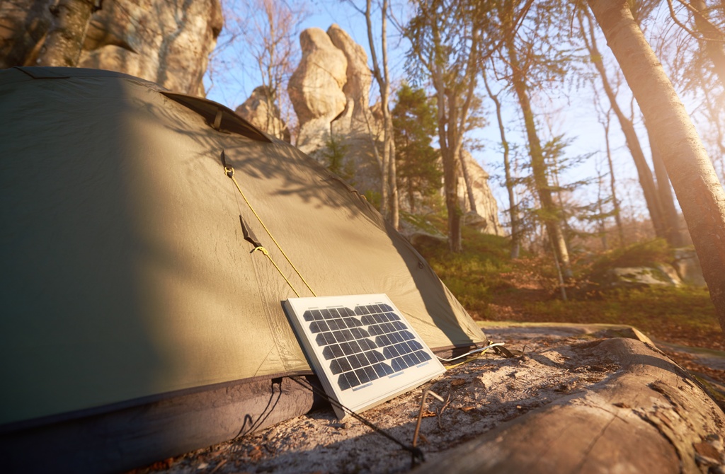 Tragbares Solarpanel, das an einem Rucksack befestigt ist, in einer sonnigen Berglandschaft.