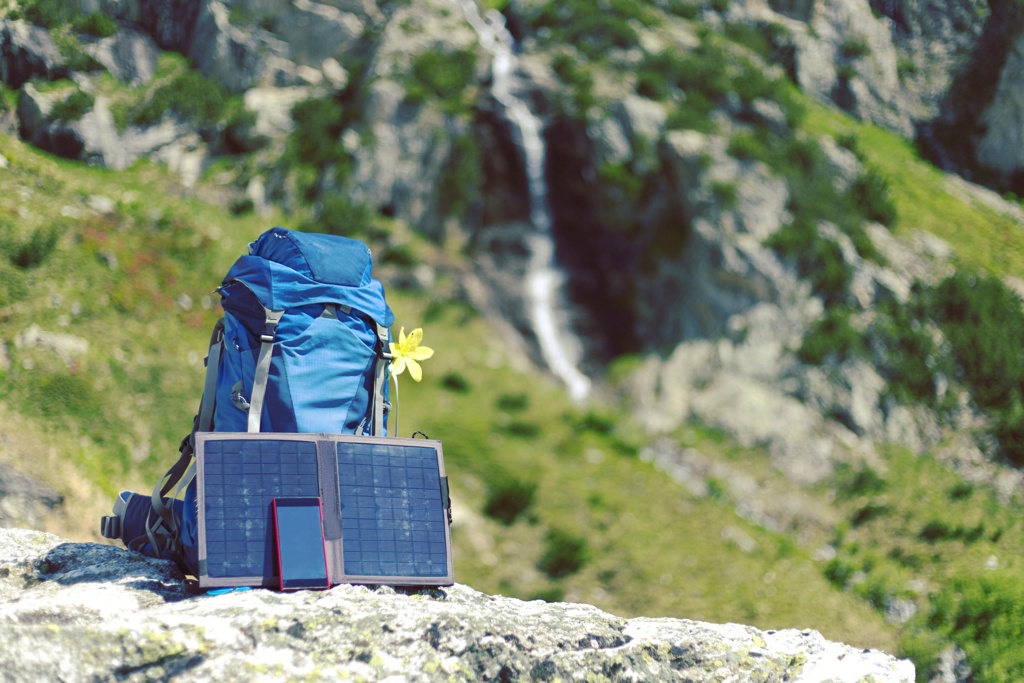 Solarpanel auf dem Boden vor einem grünen Campingzelt, ideal für umweltfreundliches Camping.