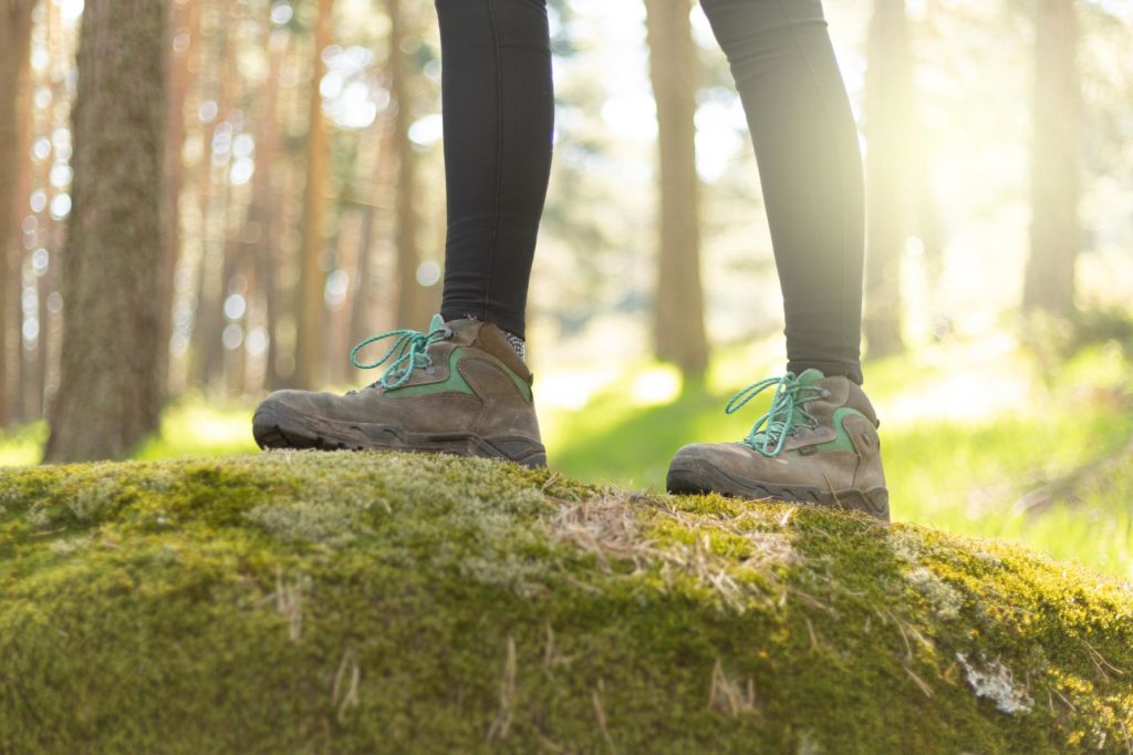 Jemand durchquert einen grünen Wald in nachhaltigen, PFC-freien Schuhen.