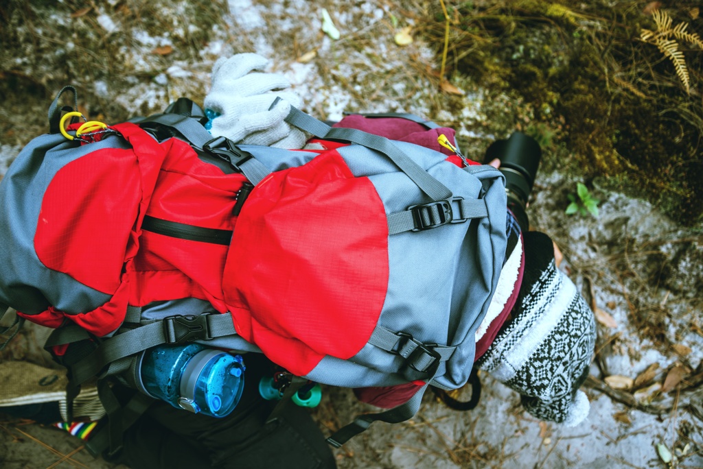 Ein gut ausgestatteter roter Fluchtrucksack mit Wasserflasche und Handschuhen, bereit für den Einsatz in einer kalten Umgebung.